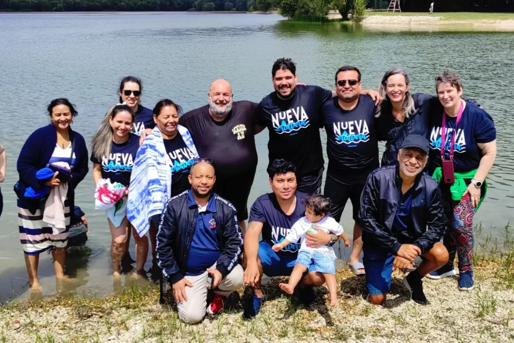 Grupo reunido após o batismo celebrando a nova vida em Cristo com alegria à beira do lago